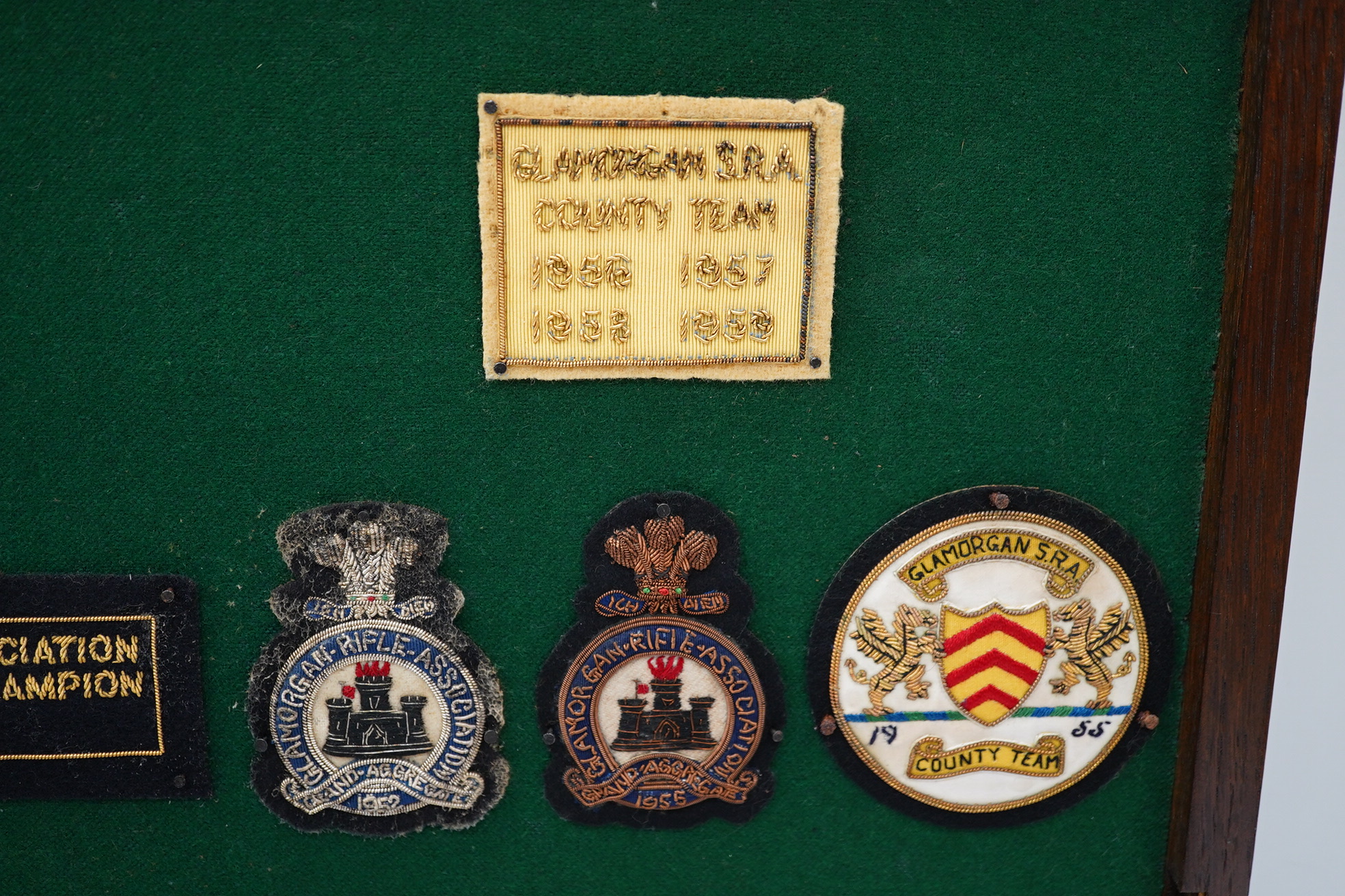 An oak cased collection of rifle and shooting medals disguised as a framed map of Glamorganshire, containing hallmarked silver medals engraved to the awardees, cloth badges for Glamorgan Rifle Association, bronze rifle a